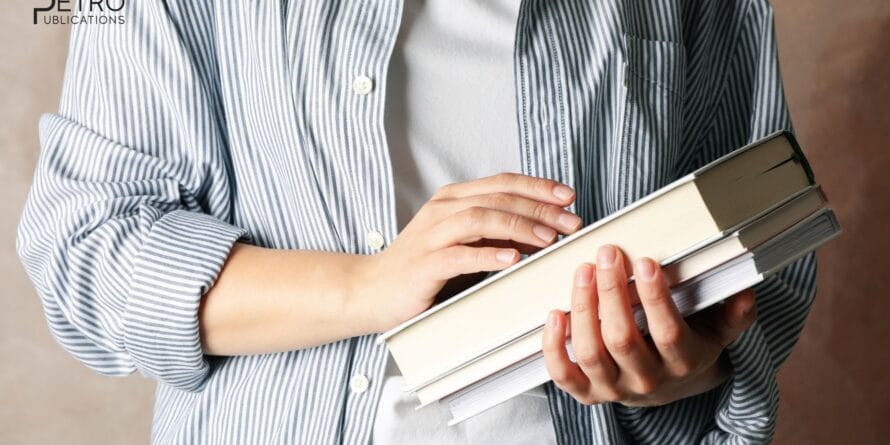 Faceless person in a striped shirt holding books - can you use old PE exam reference manuals - insights from Petro Publications.